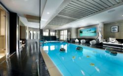 luxury-indoor-swimming-pool-with-blue-water-and-black-tile-floor-side-pool-and-cool-bench
