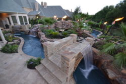garden-and-patio-large-backyard-lazy-river-pool-design-with-rock-and-garden-with-lounge-area-in-the-middle-plus-bridge-with-waterfall-ans-stone-floor-tiles-ideas-backyard-lazy-river