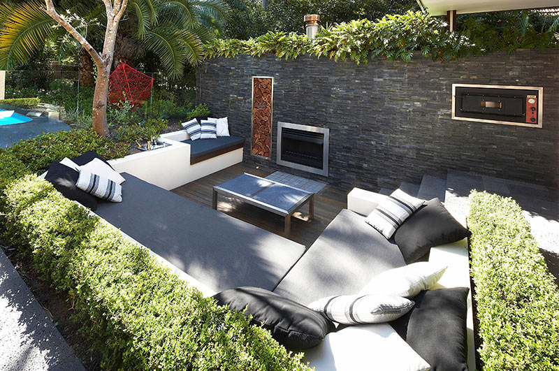 Outdoor-Living-with-Sunken-Lounge-hedges-and-stone-wall-with-fireplace-oven