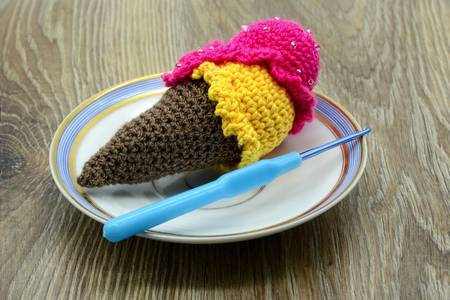 97946960-crochet-ice-cream-cone-made-of-wool-and-crochet-hook-on-table-background